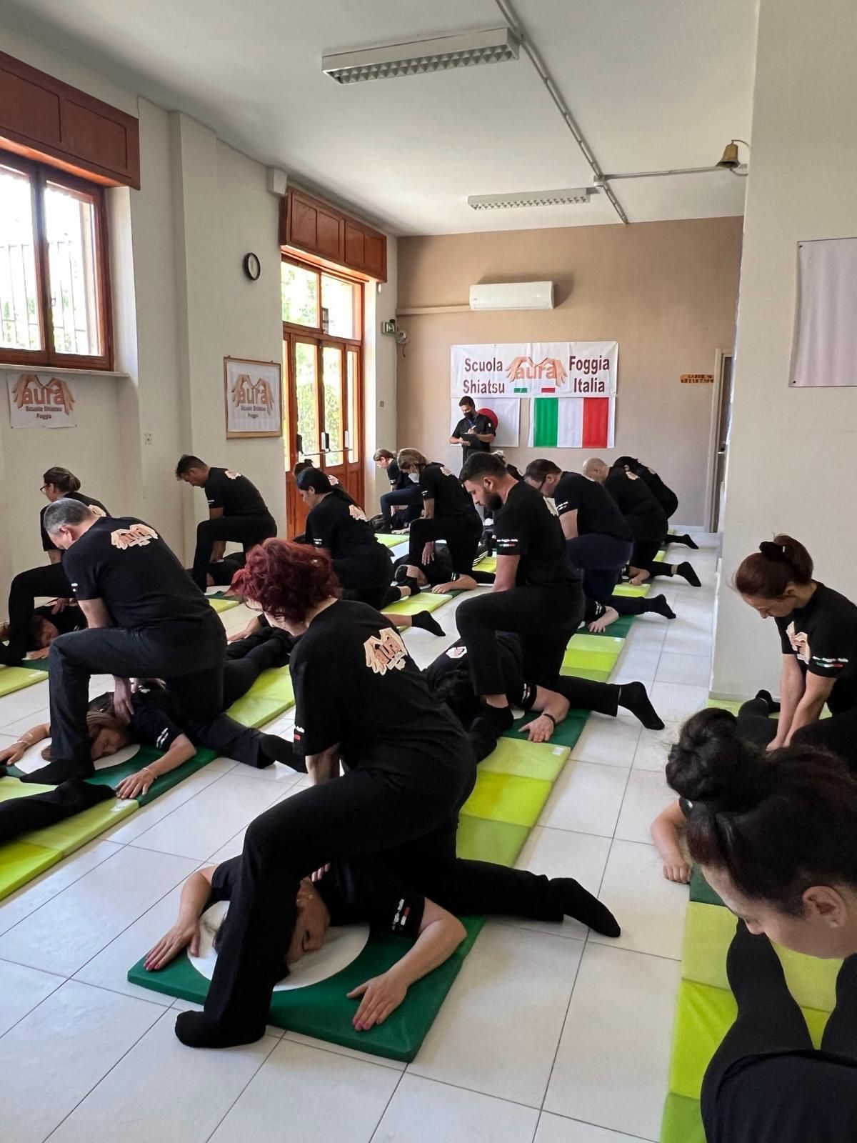 Un gruppo di persone è sdraiato su stuoie verdi in una stanza