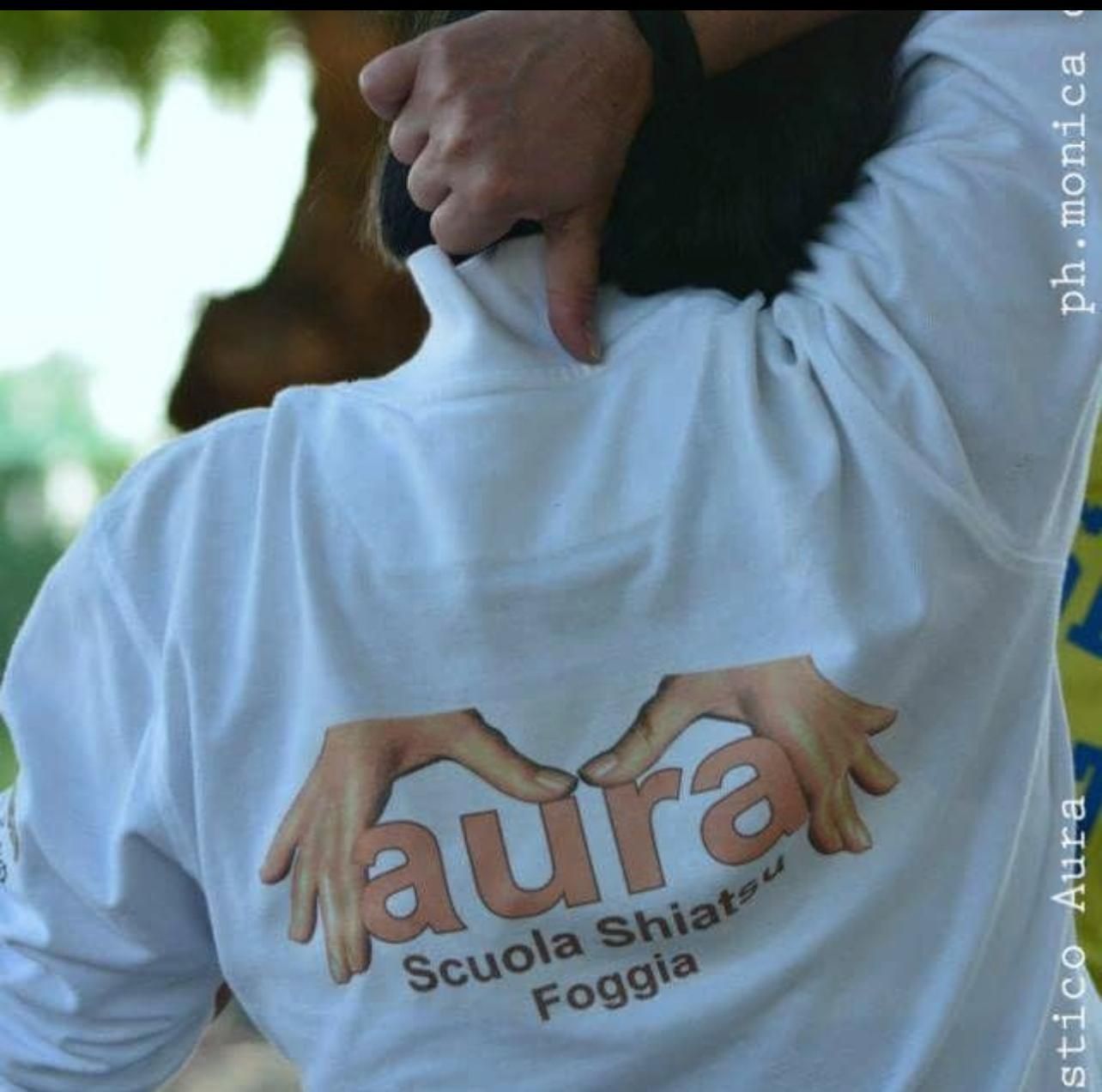 Una persona che indossa una maglietta bianca con la parola aura sopra