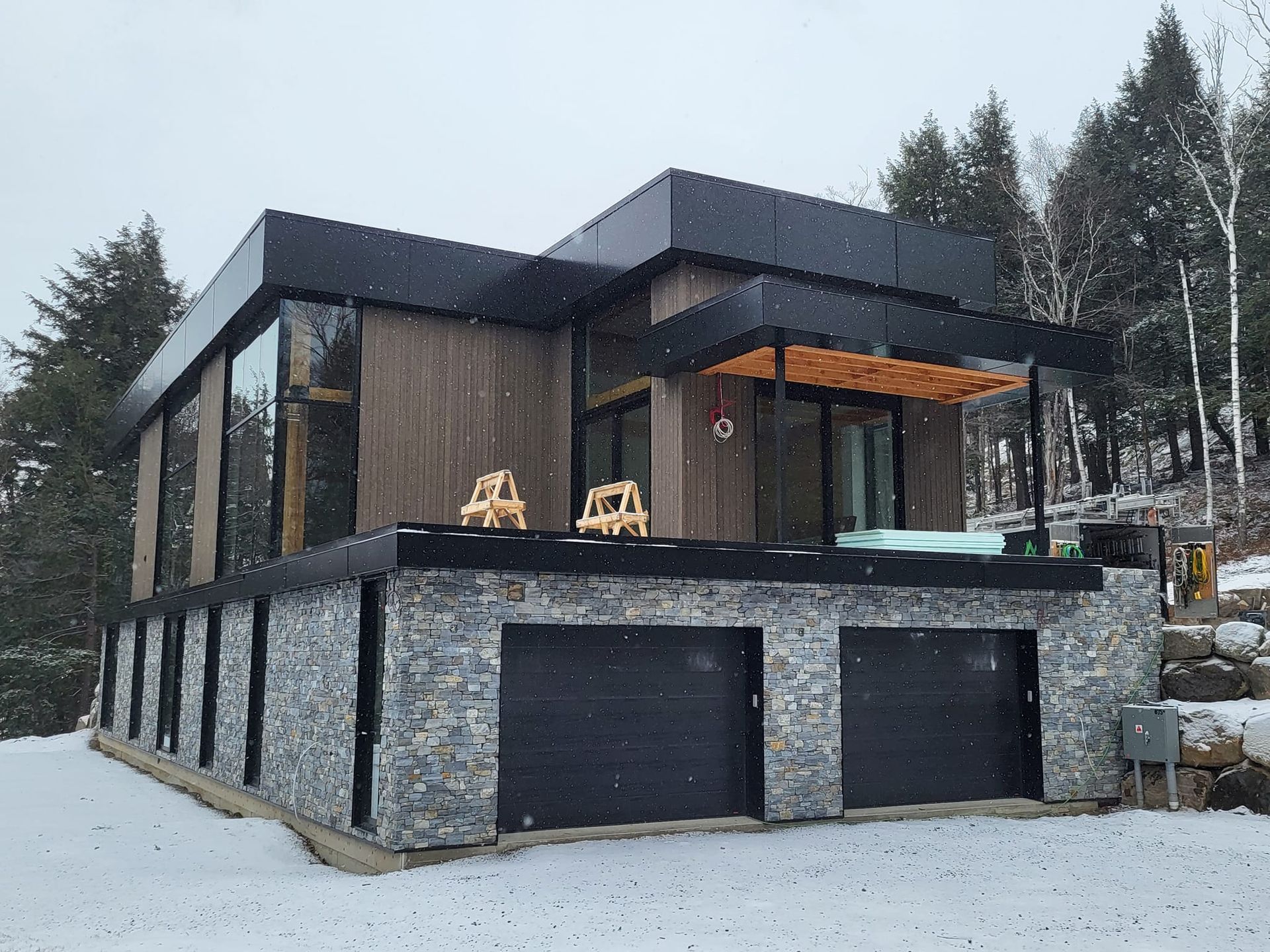 Une maison moderne avec un grand garage et un jacuzzi dans la neige.