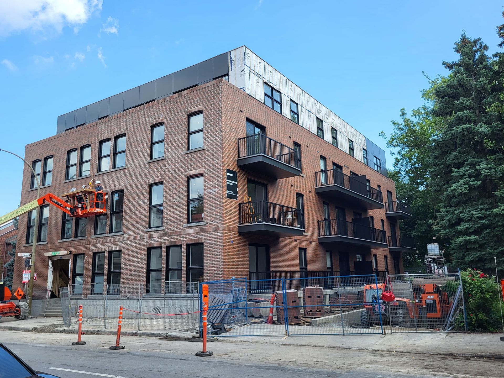 Un grand bâtiment en briques est en construction par une journée ensoleillée.