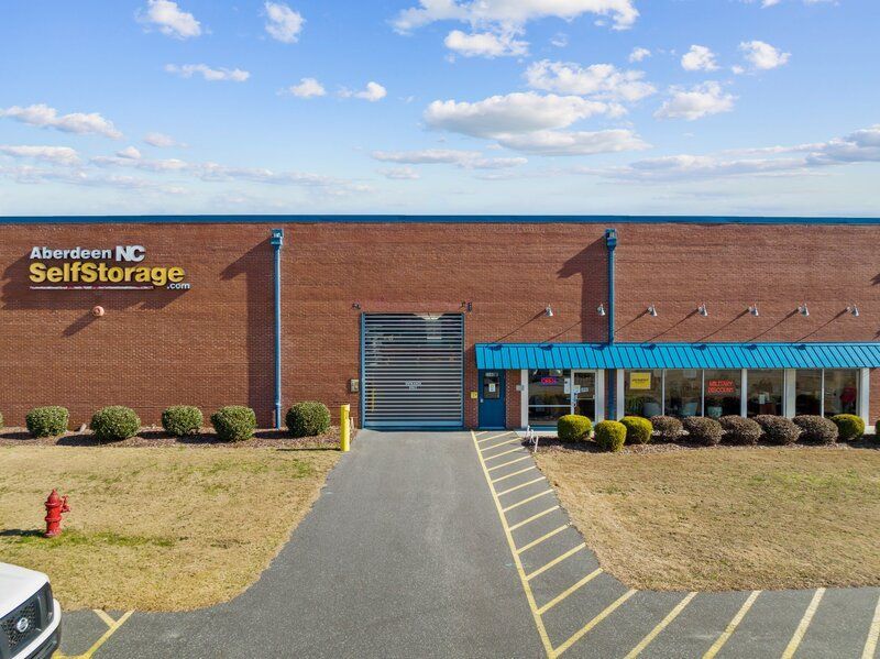 Exterior of Aberdeen NC Self Storage facility with brick facade, blue trim, and blue sky.