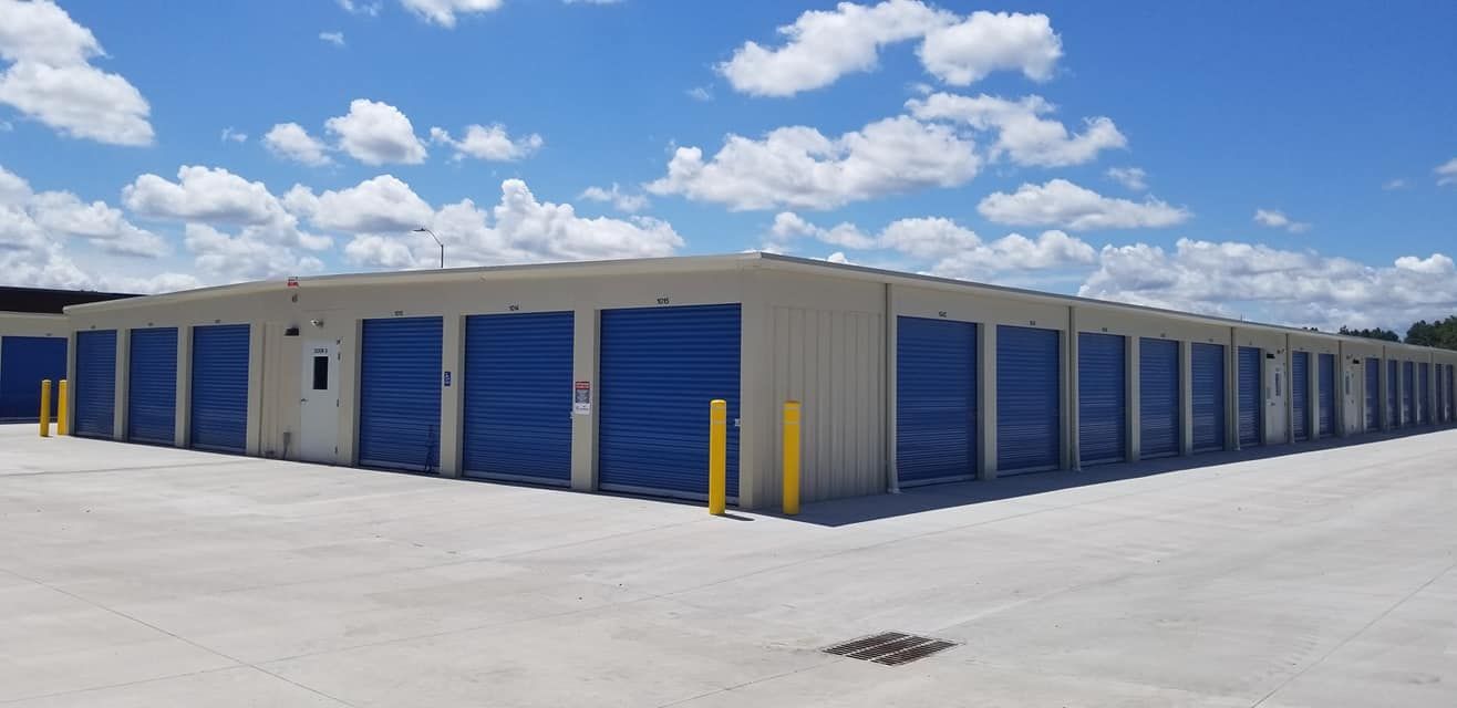 Storage units with blue doors under a cloudy blue sky.