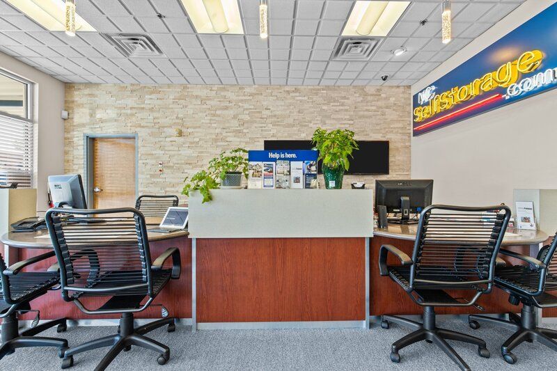 Office interior with a front desk, chairs, computers, and a sign for storage.