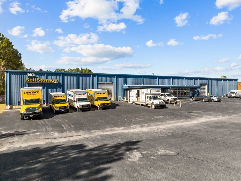 A storage facility with several yellow moving trucks parked outside on a sunny day.