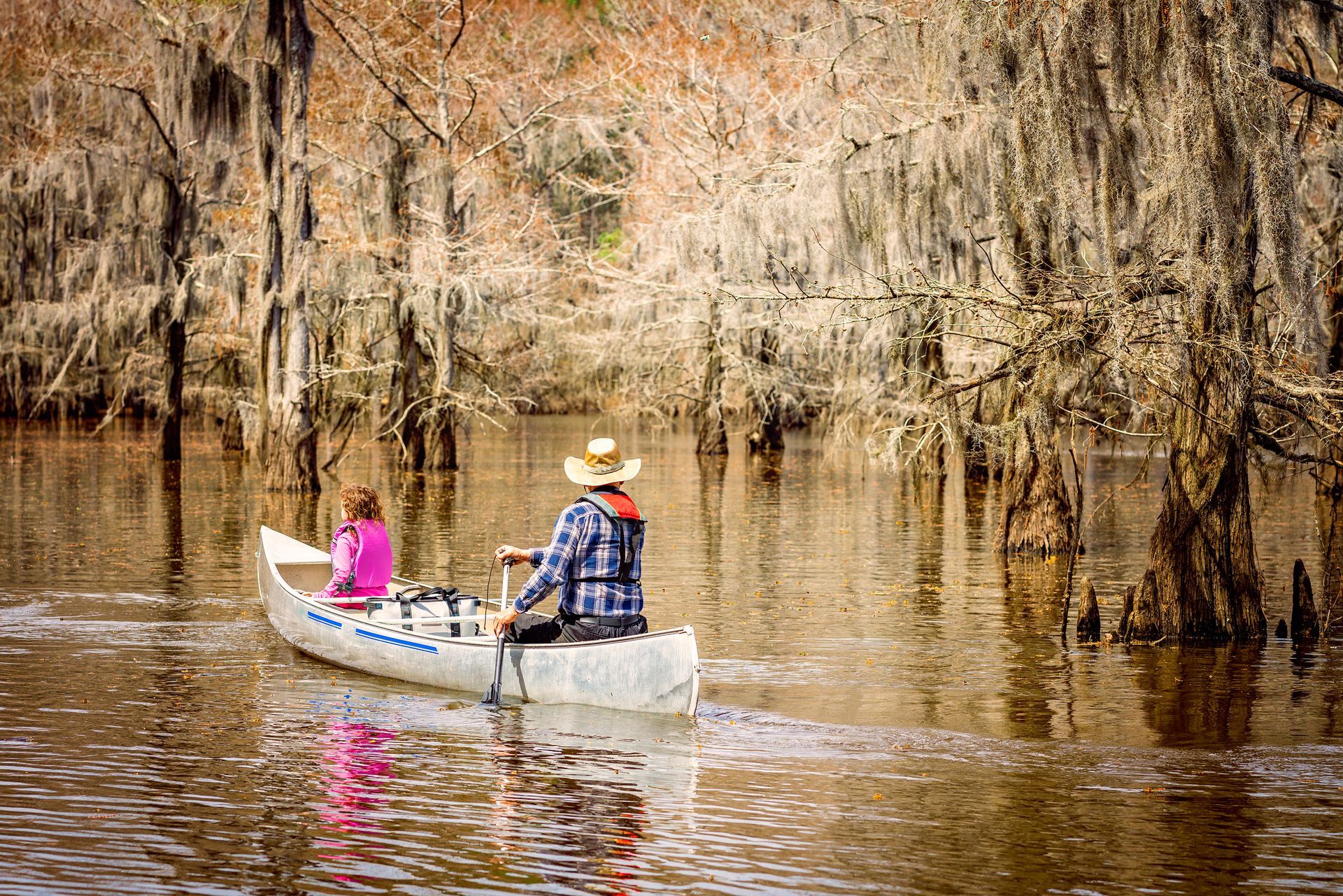 A man and a woman are in a canoe on a river.