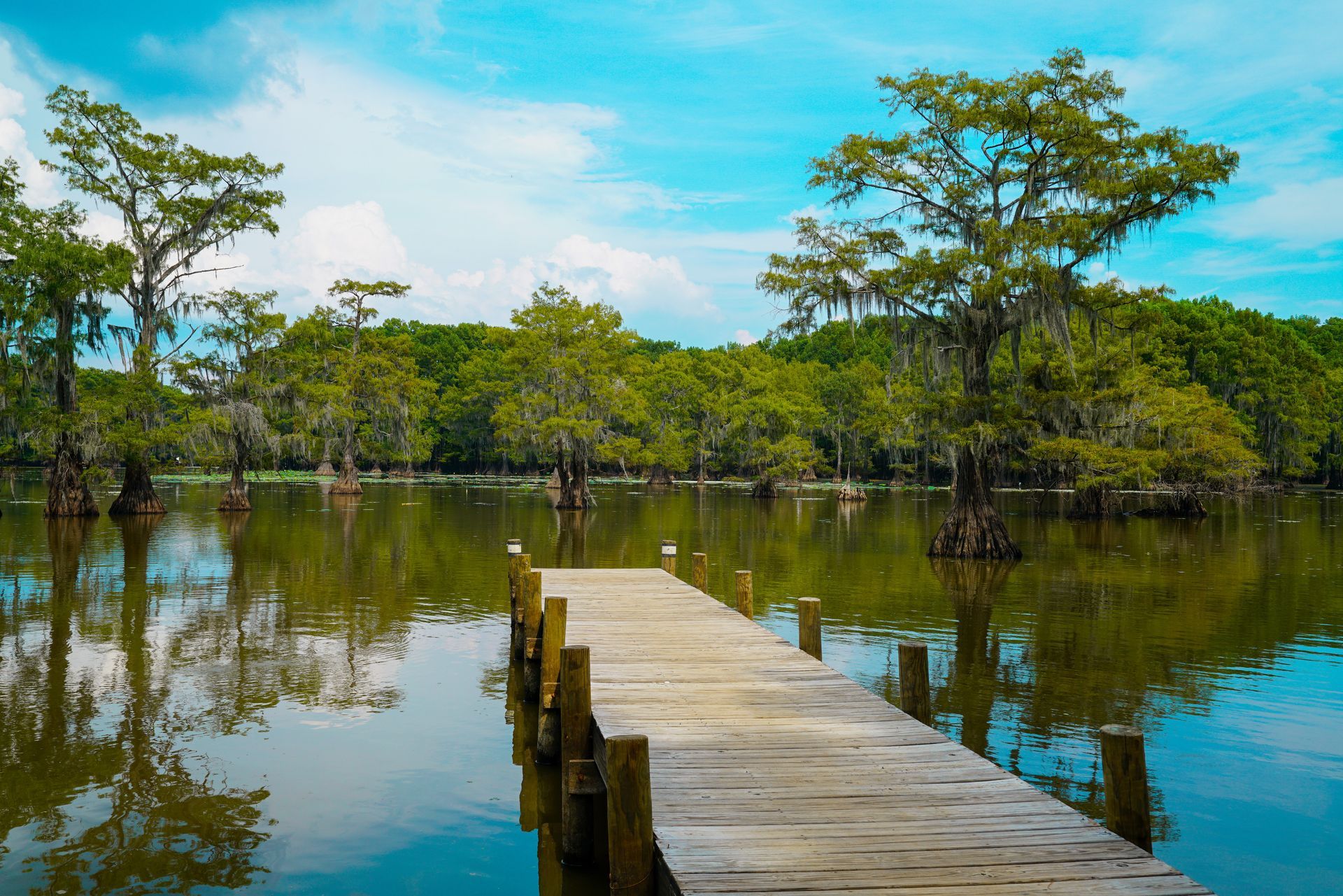 A wooden dock in the middle of a lake with trees in the background.