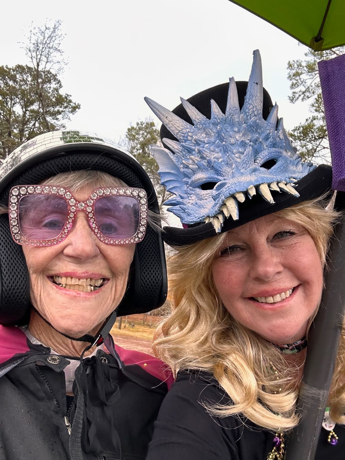 Two women are posing for a picture and one of them is wearing a dragon mask.
