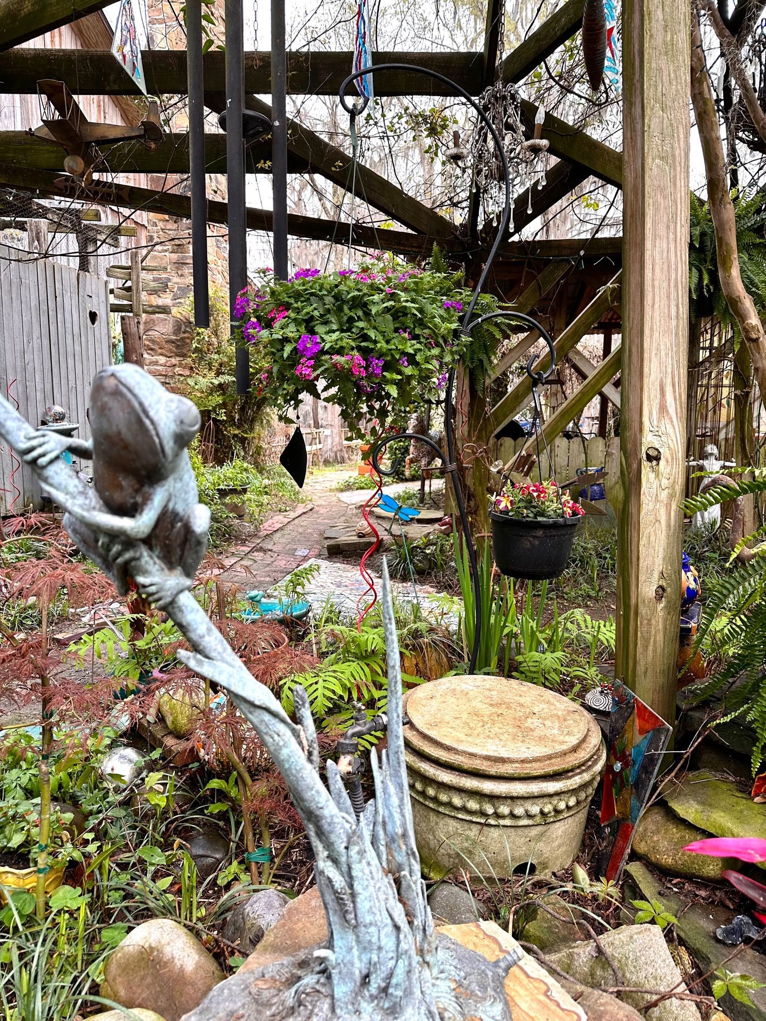 There is a statue of a frog in the middle of a garden.