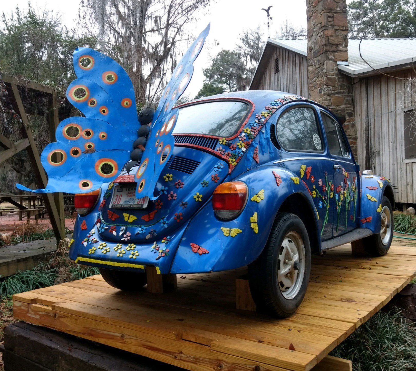 A blue car with a butterfly wing on the back