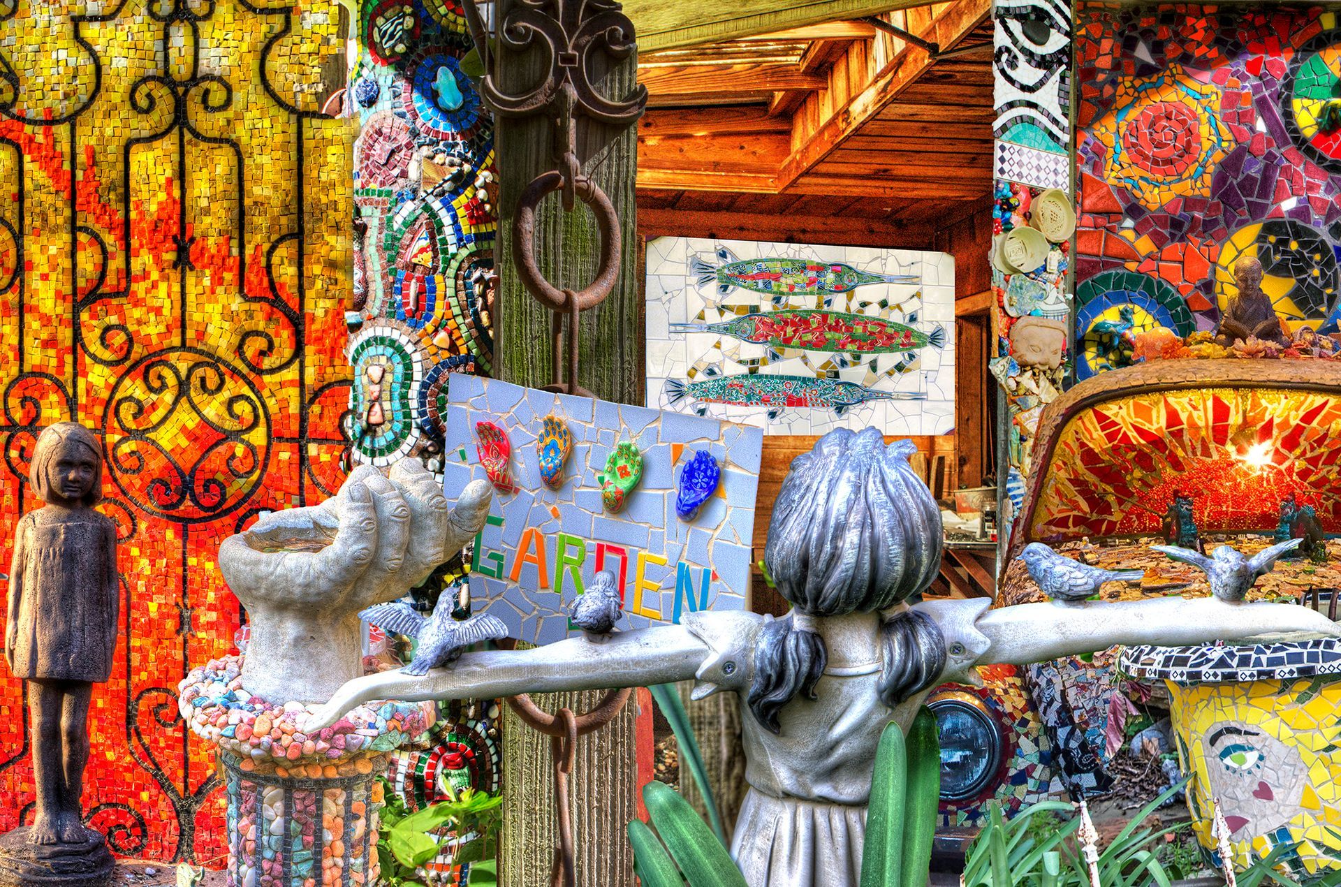 A statue of a woman holding a sign in front of a mosaic wall.