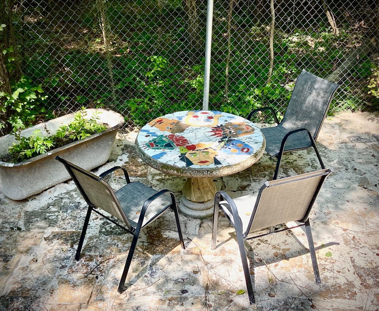 A table and chairs are sitting in front of a chain link fence.