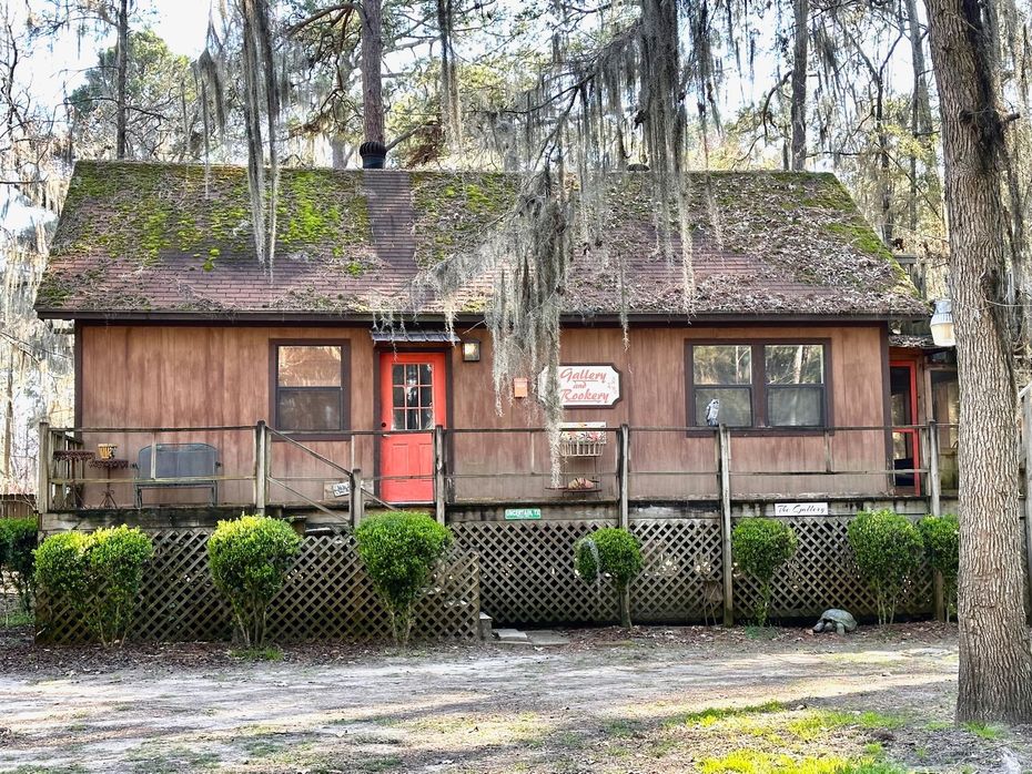 A small wooden house with a red door in the middle of a forest.