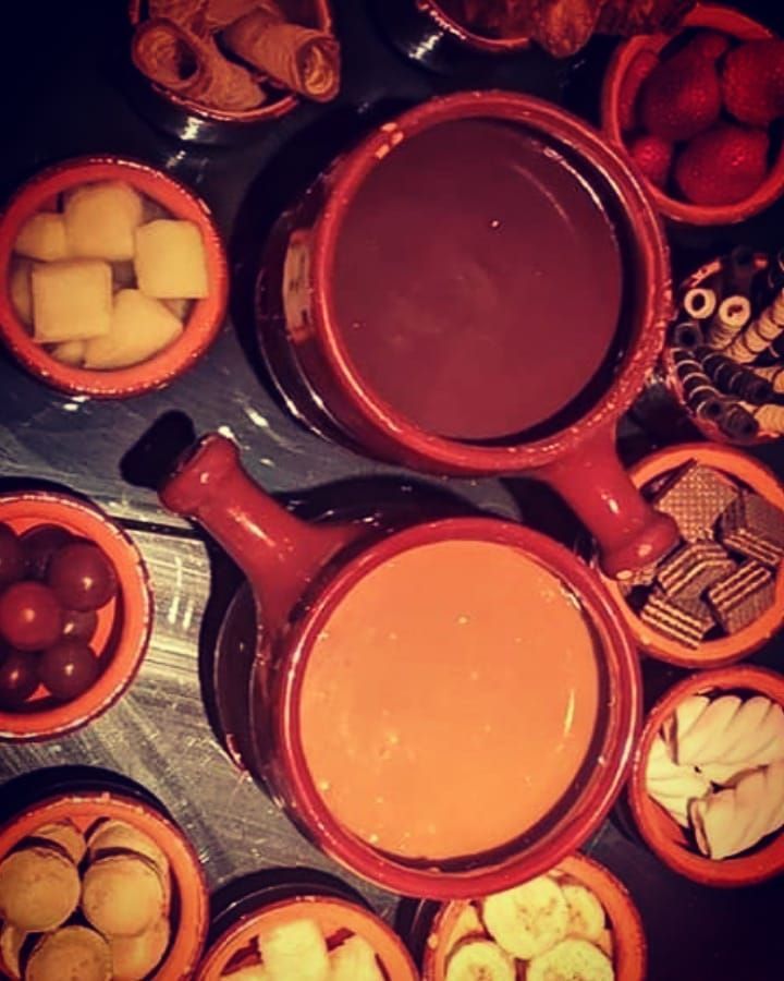 Uma mesa coberta com tigelas de comida, incluindo fondue de chocolate