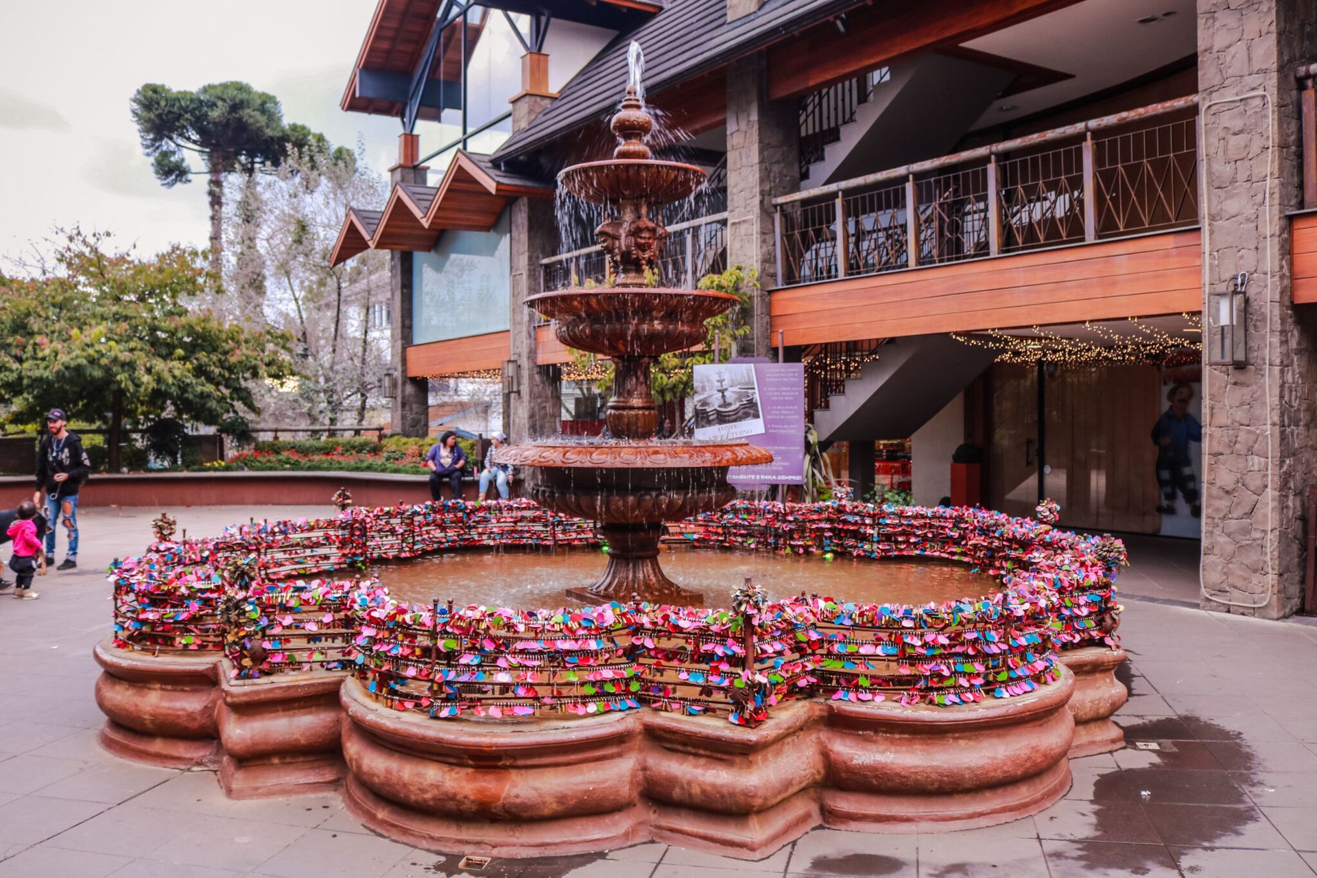 Uma fonte está cercada por flores em frente a um edifício