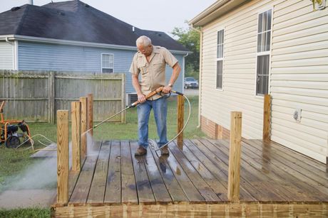 old man power washing the wooden deck