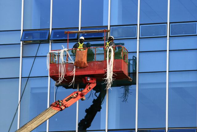 two men on a cheery picker is cleaning commercial windows