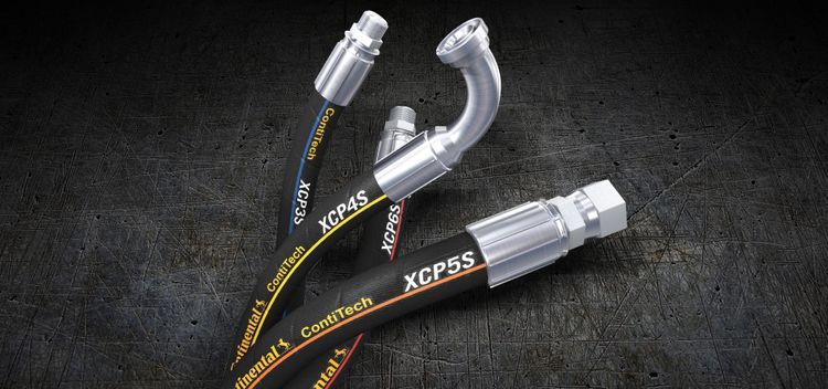 Trois tuyaux hydrauliques sont posés les uns sur les autres sur une table.