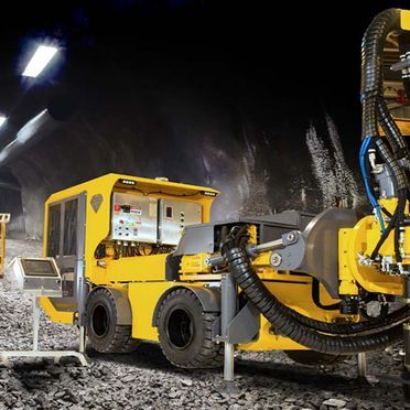 Un camion jaune est garé dans un tunnel avec un tuyau attaché dessus