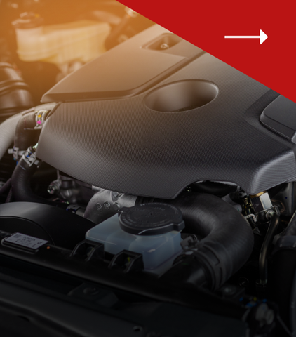 A close-up view of a car engine compartment with a black engine cover and a translucent fluid reservoir.
