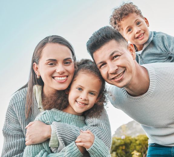 A family is posing for a picture together and smiling for the camera.