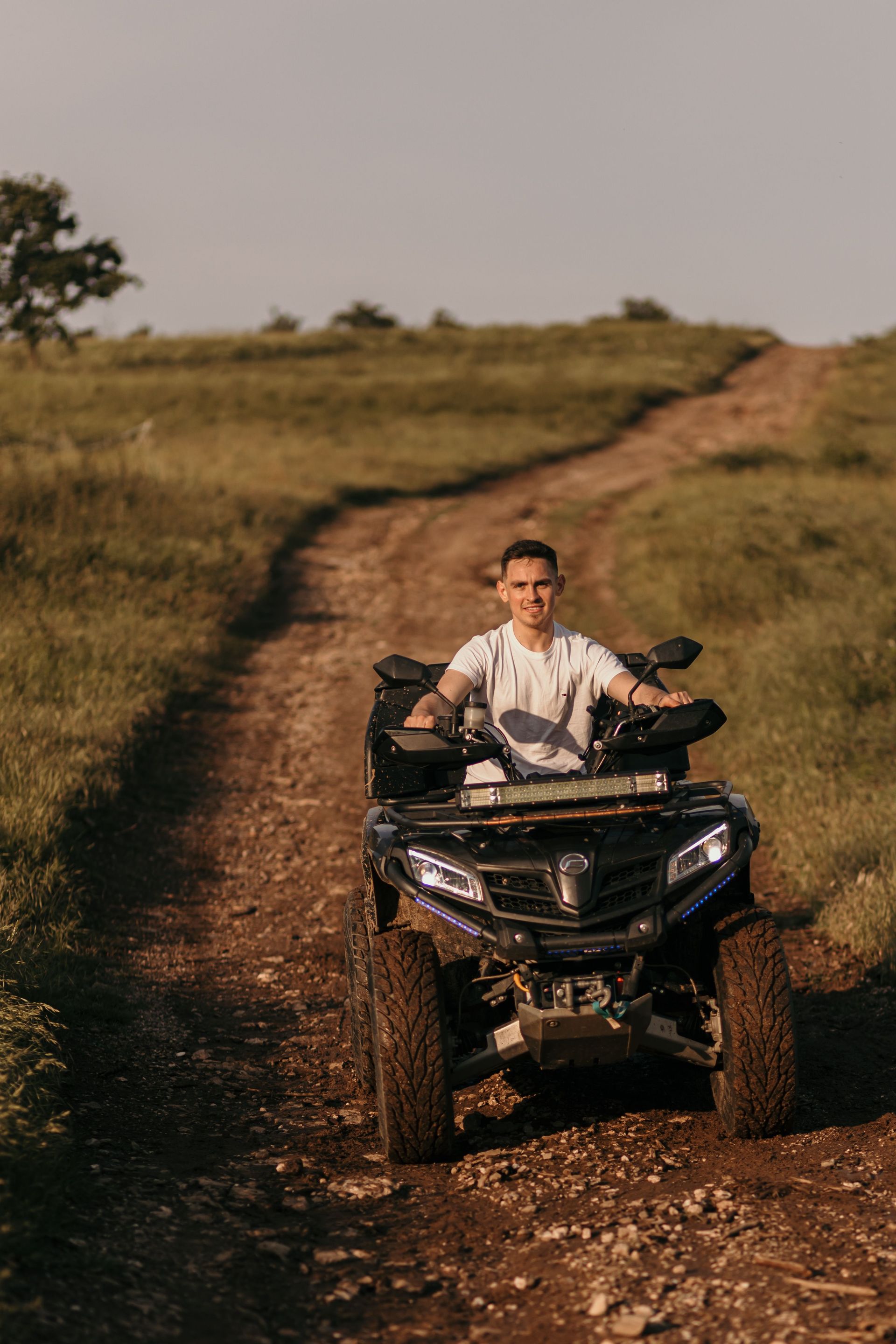 A side-by-side UTV parked on a dirt trail on a rural Texas ranch property with open pasture in the b