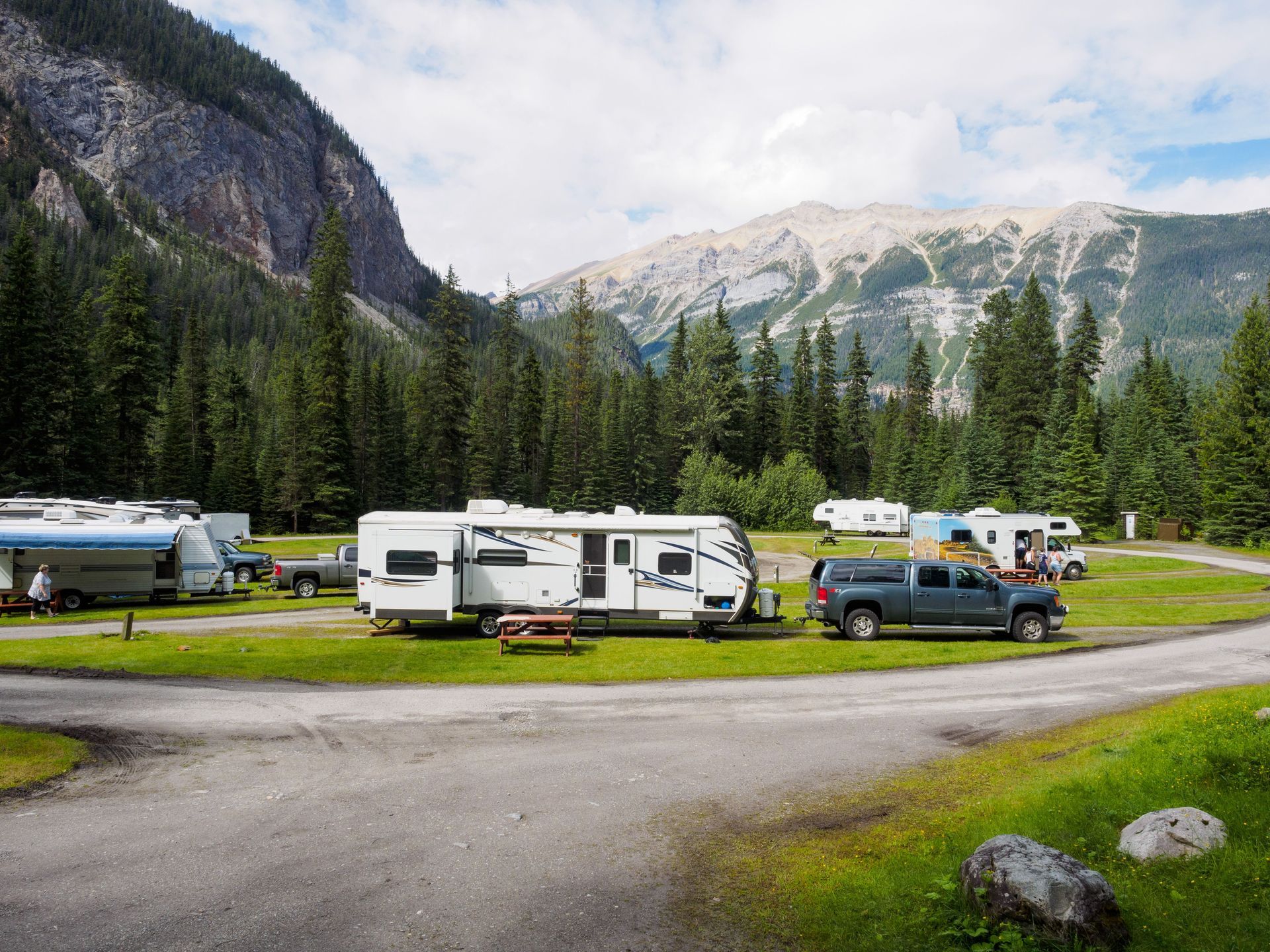 Travel trailers and motorhomes parked at a summer campground, showing why Texas RV owners need proper coverage