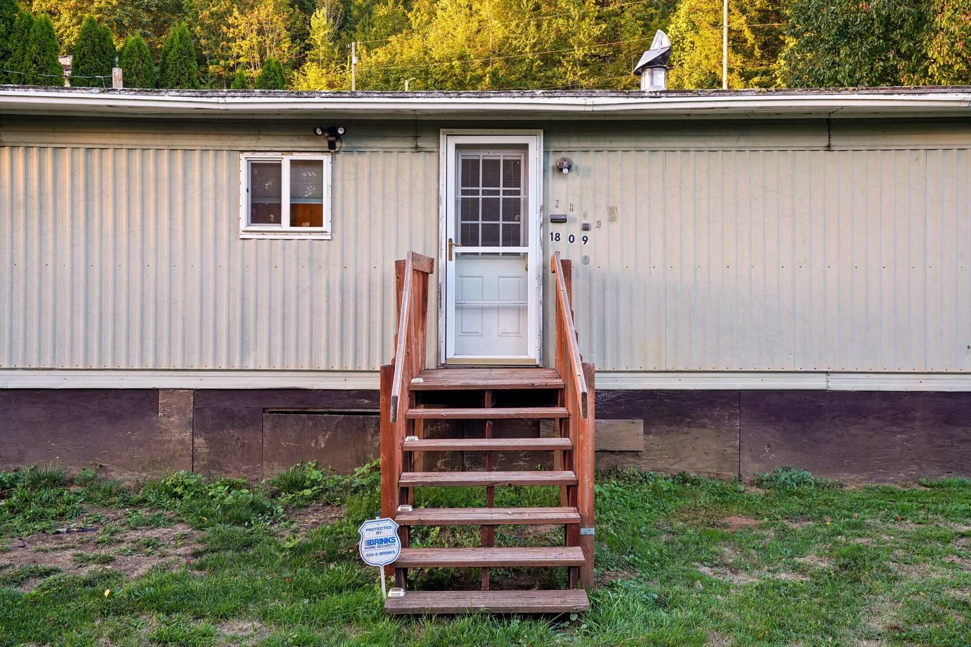 A manufactured home on a rural Texas property with a covered porch and detached carport under a wide