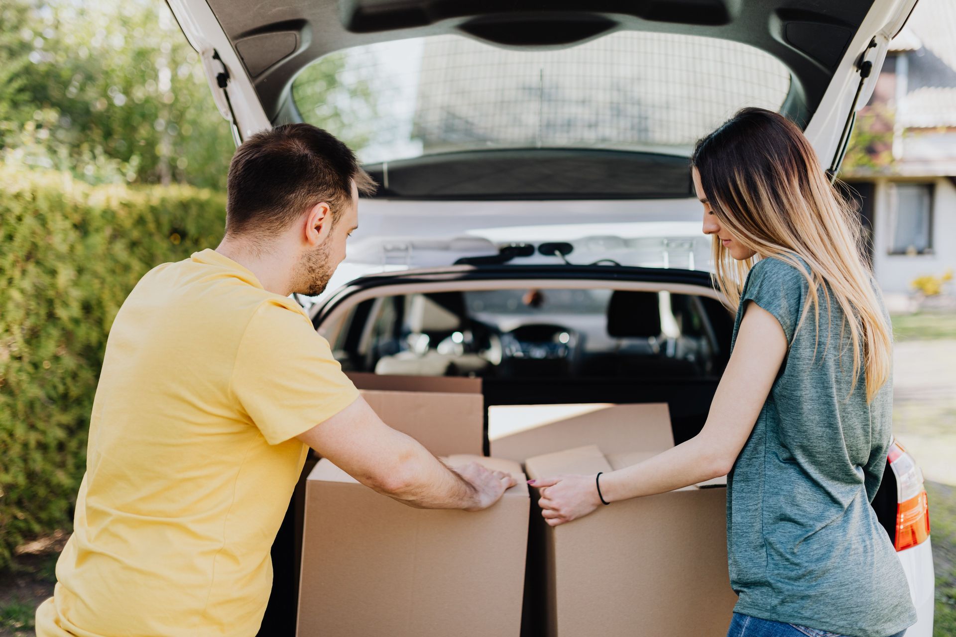 A family loading moving boxes into a car for a college dorm move-in day, insurance decisions ahead
