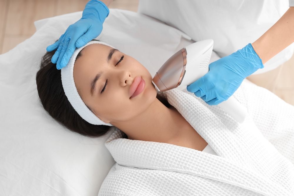 A woman is getting a laser treatment on her face in a beauty salon.