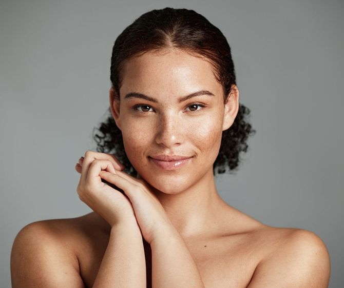 A close up of a woman 's face with her hands on her chin.