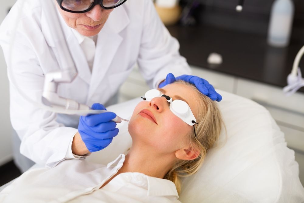 A woman is getting a laser treatment on her face.