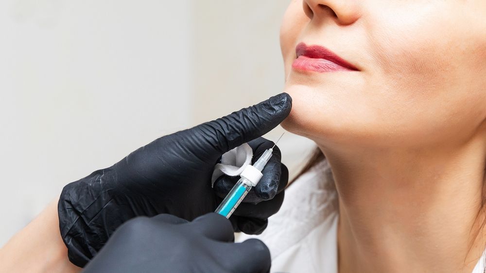 A woman is getting a botox injection in her face.