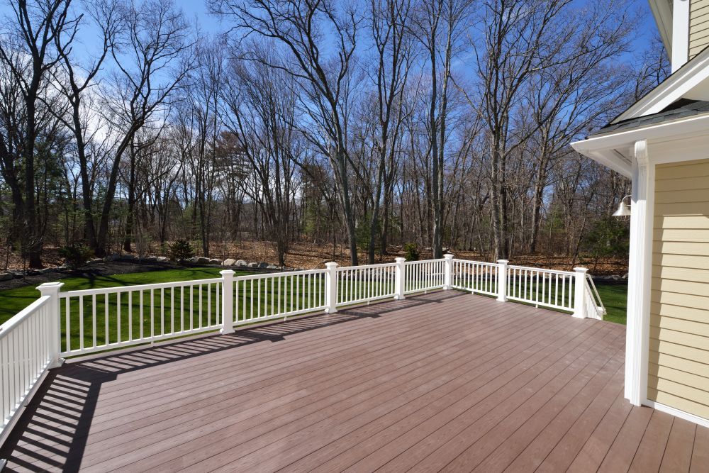 A large deck with a white railing and trees in the background