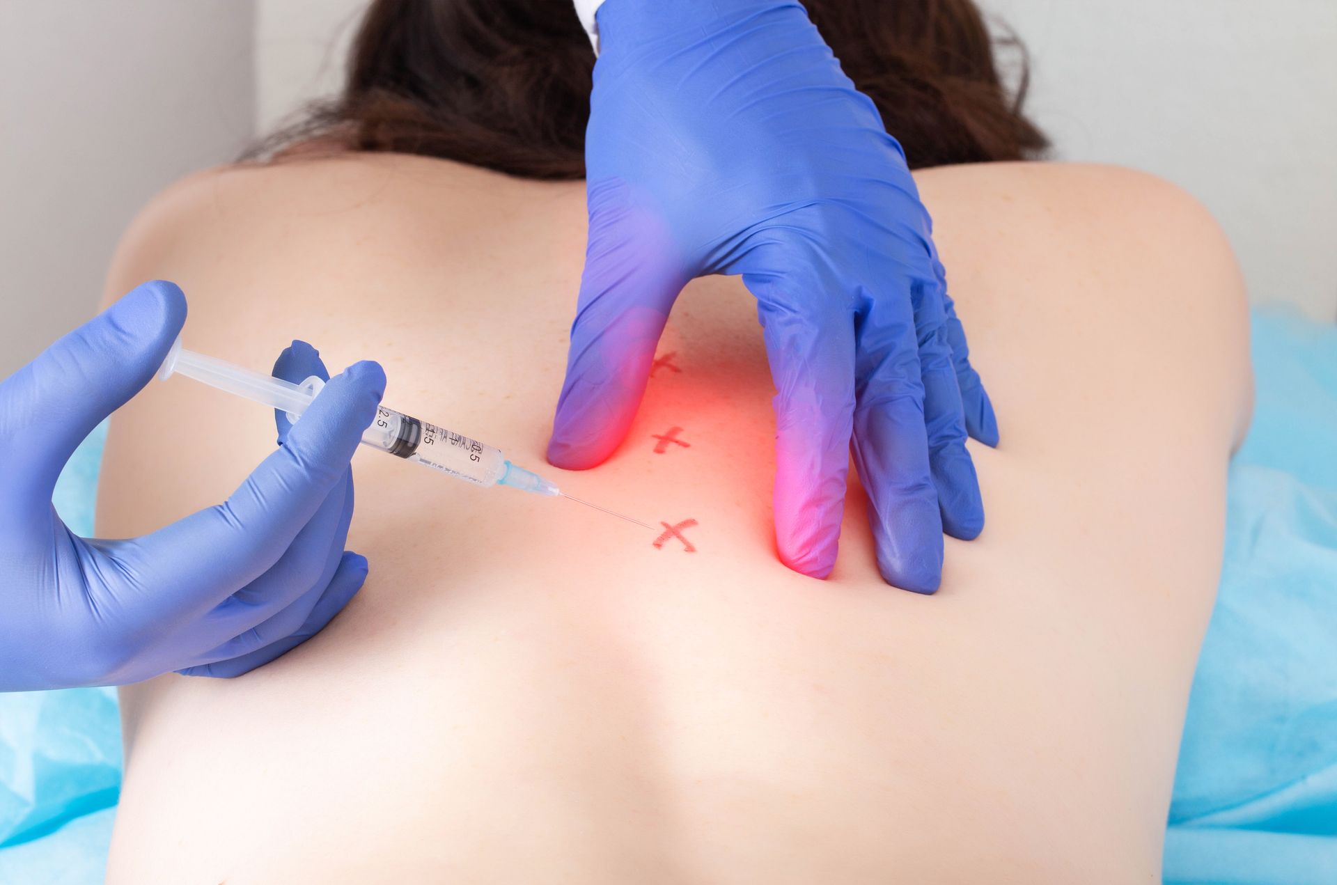 Hands inject a glowing red spot on a person’s upper back with a syringe