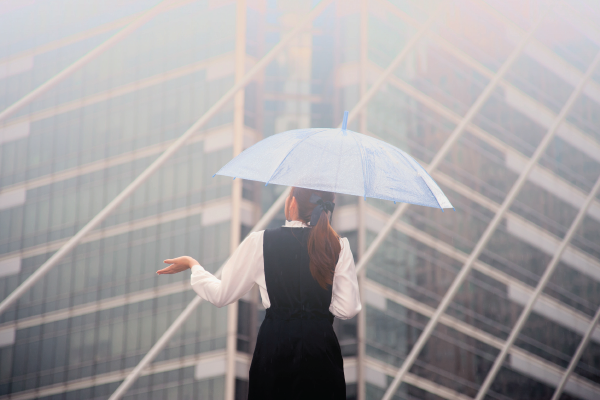 A woman is holding an umbrella in front of a building.