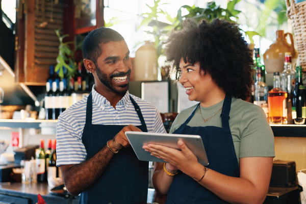 A man and a woman are looking at a tablet in a restaurant.