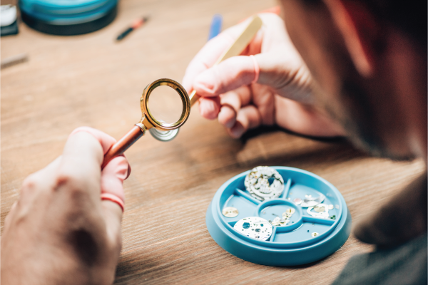 A man is working on a watch with a magnifying glass.