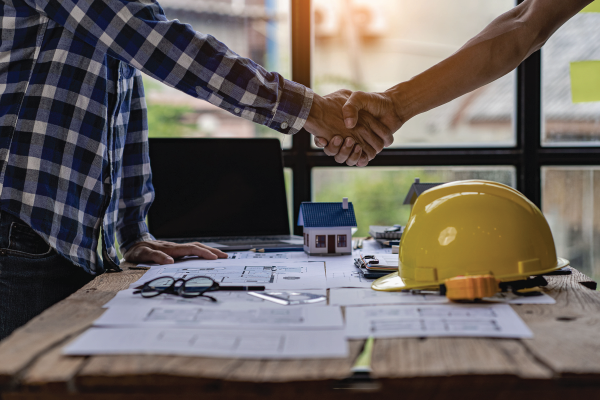 Two men are shaking hands over a wooden table.