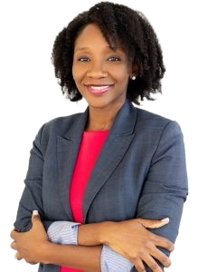 Woman with curly hair smiles, arms crossed, wearing a navy blazer over a red top.