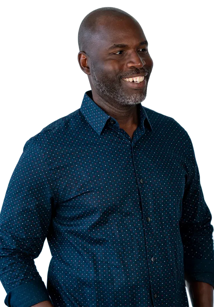 Man smiling, wearing a dark blue shirt with small white dots. He is looking off to the side.