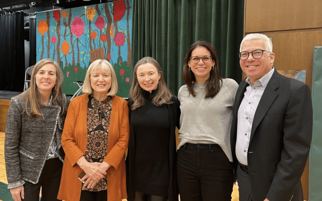 Five people smiling, posing in front of a colorful backdrop.