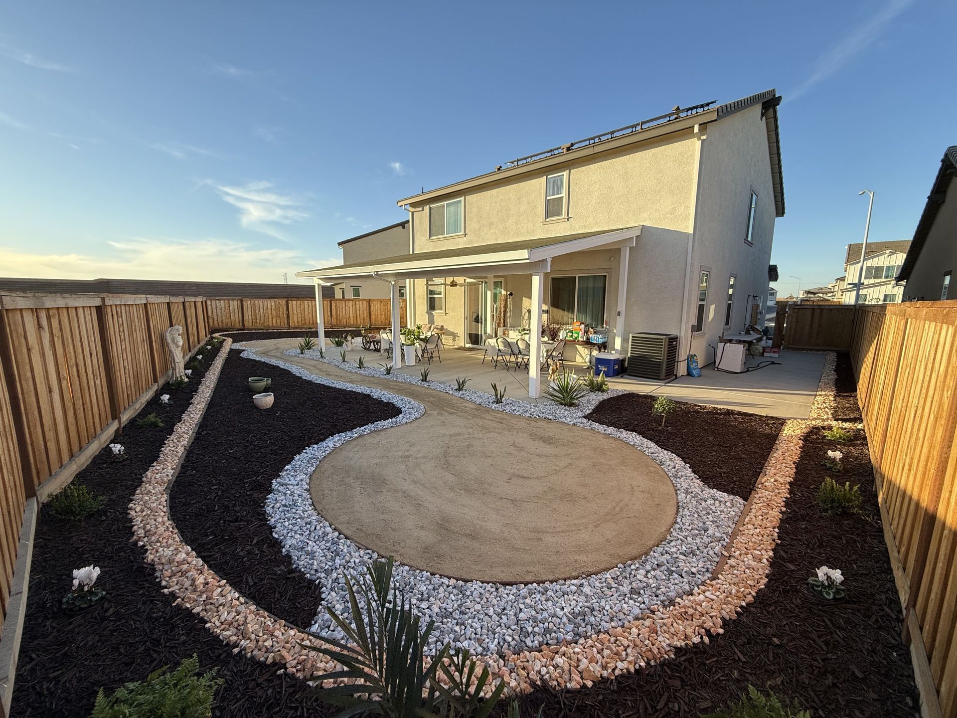 Wide view of full patio landscape with rock, plants, and planting soil in Stockton.