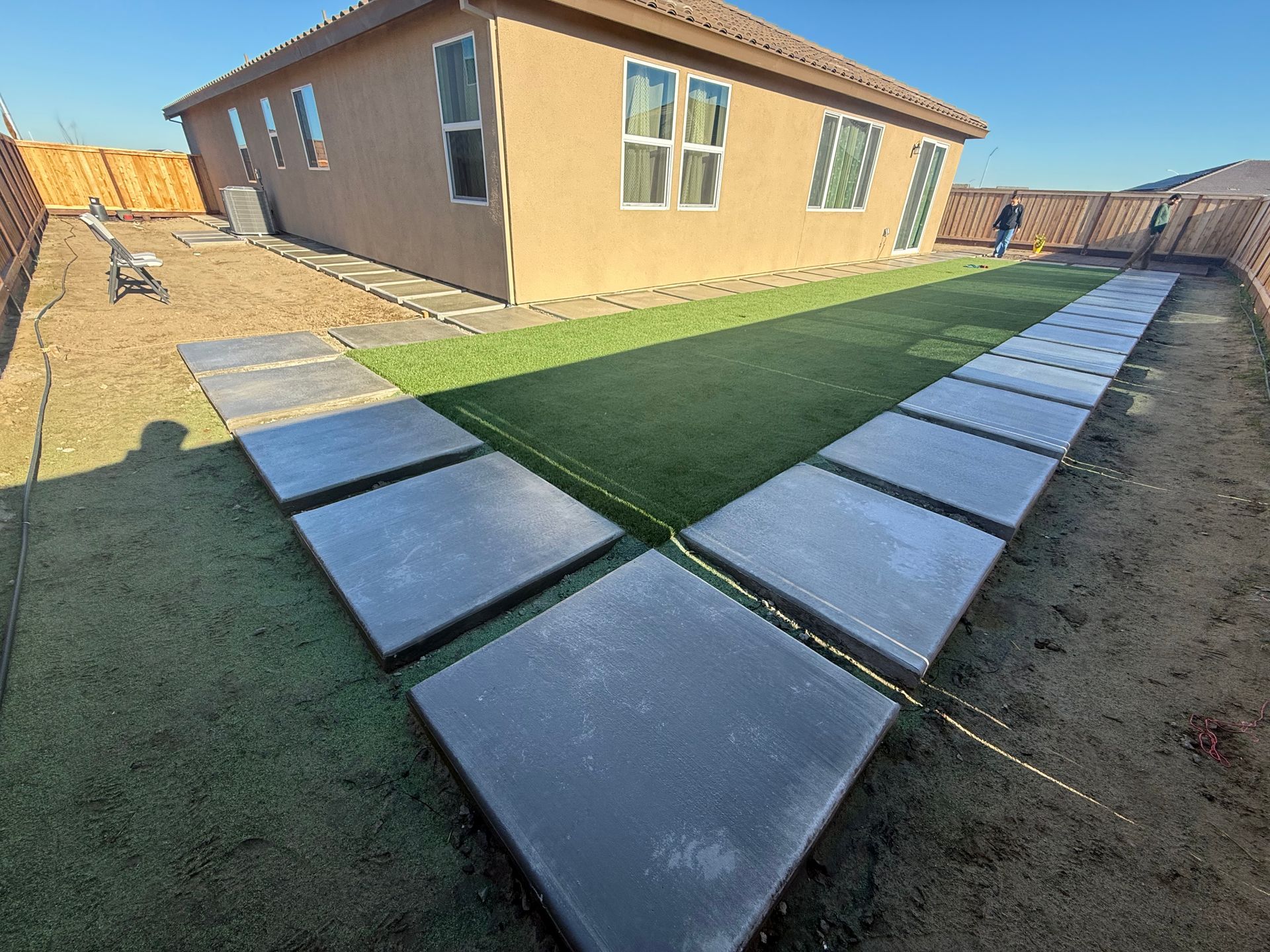 Stamped concrete and turf backyard design in Stockton landscaping project.

