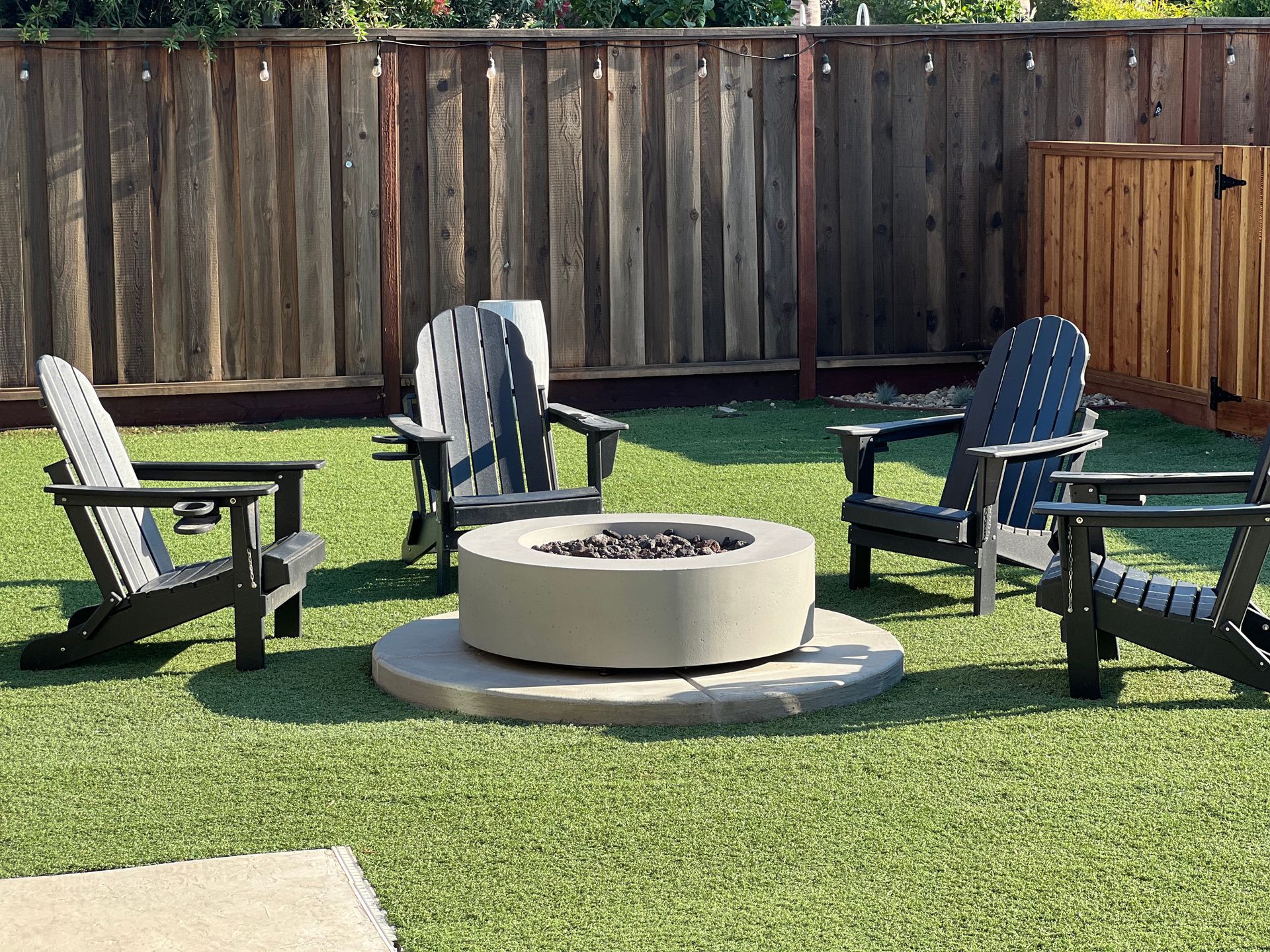 Turf installation and custom firepit in backyard landscape design.