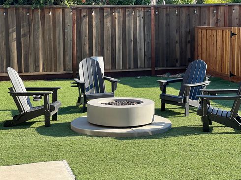 Turf installation and custom firepit in backyard landscape design.
