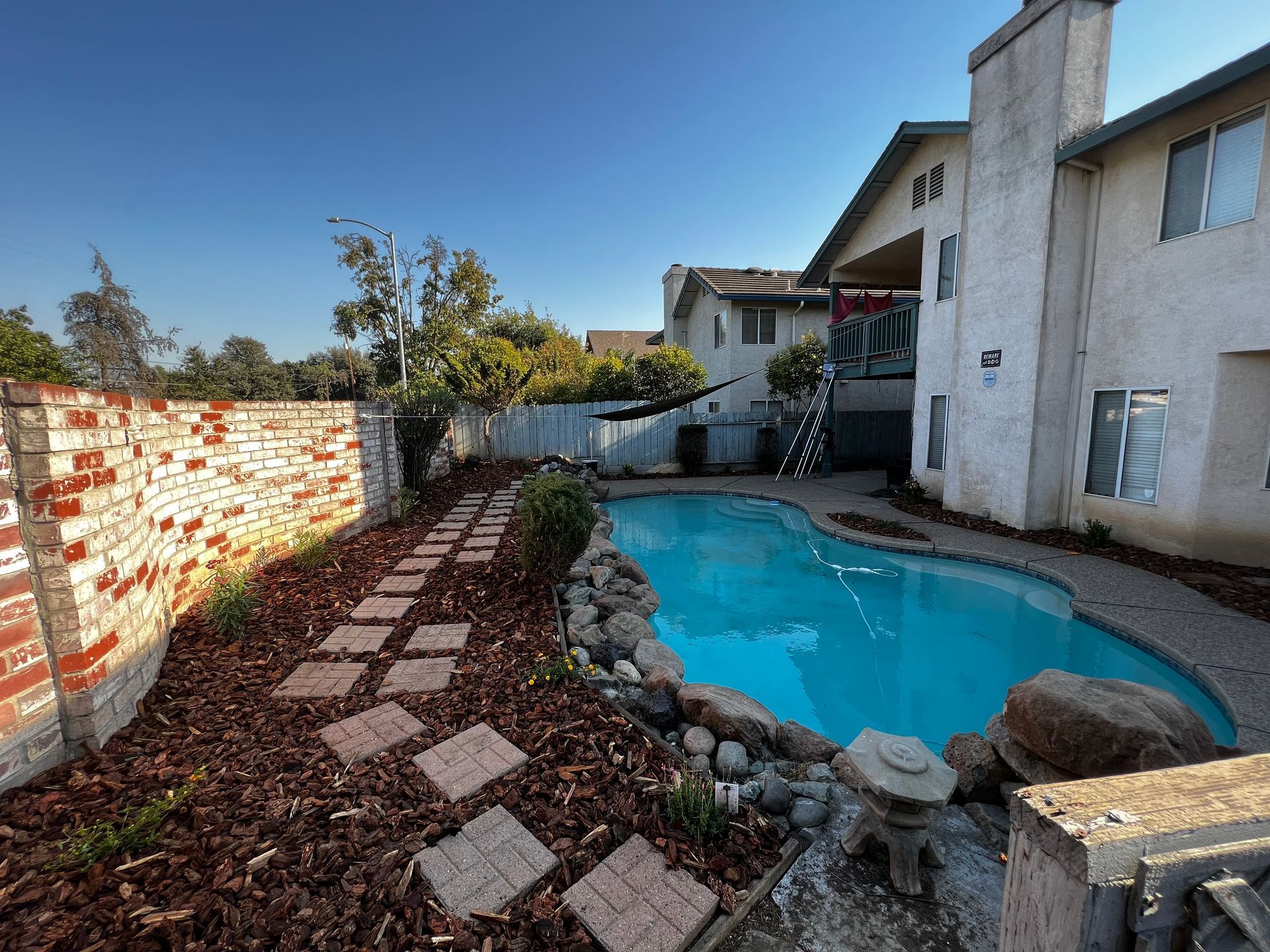 Landscape design with rock, mulch, and concrete by pool in Stockton CA.
