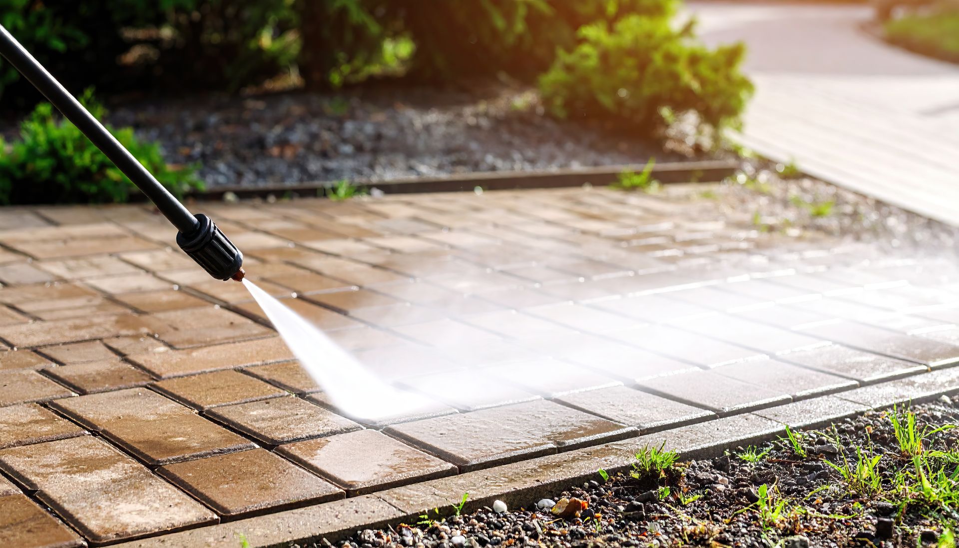 Pressure washer cleaning a brick patio, removing dirt.