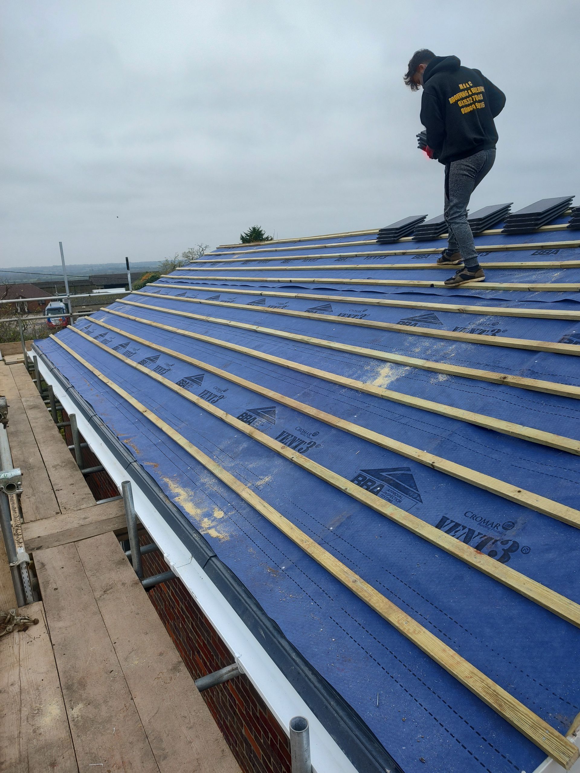 A man is standing on top of a blue roof.