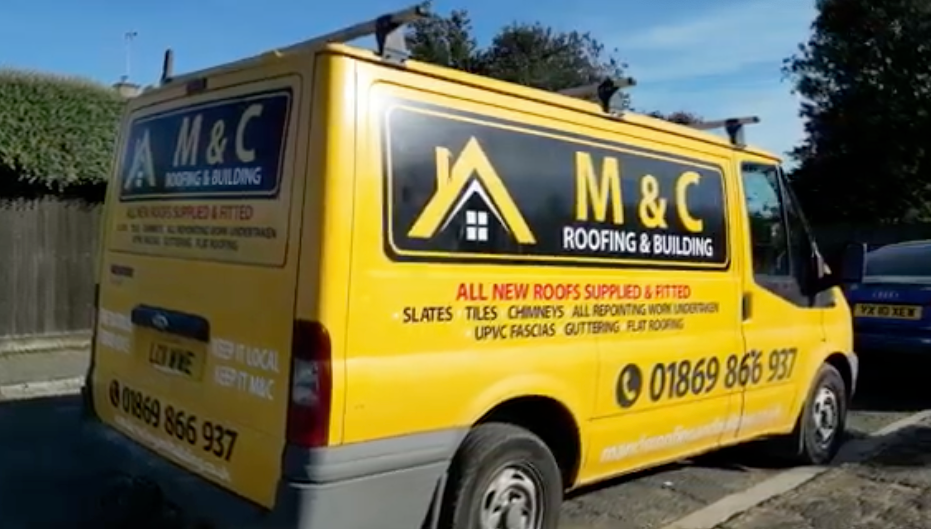A yellow m & c roofing and building van is parked on the side of the road.