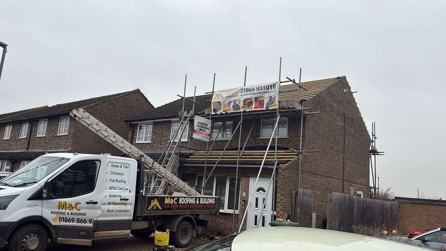 House under construction with scaffolding, a banner, and a work van parked in front.